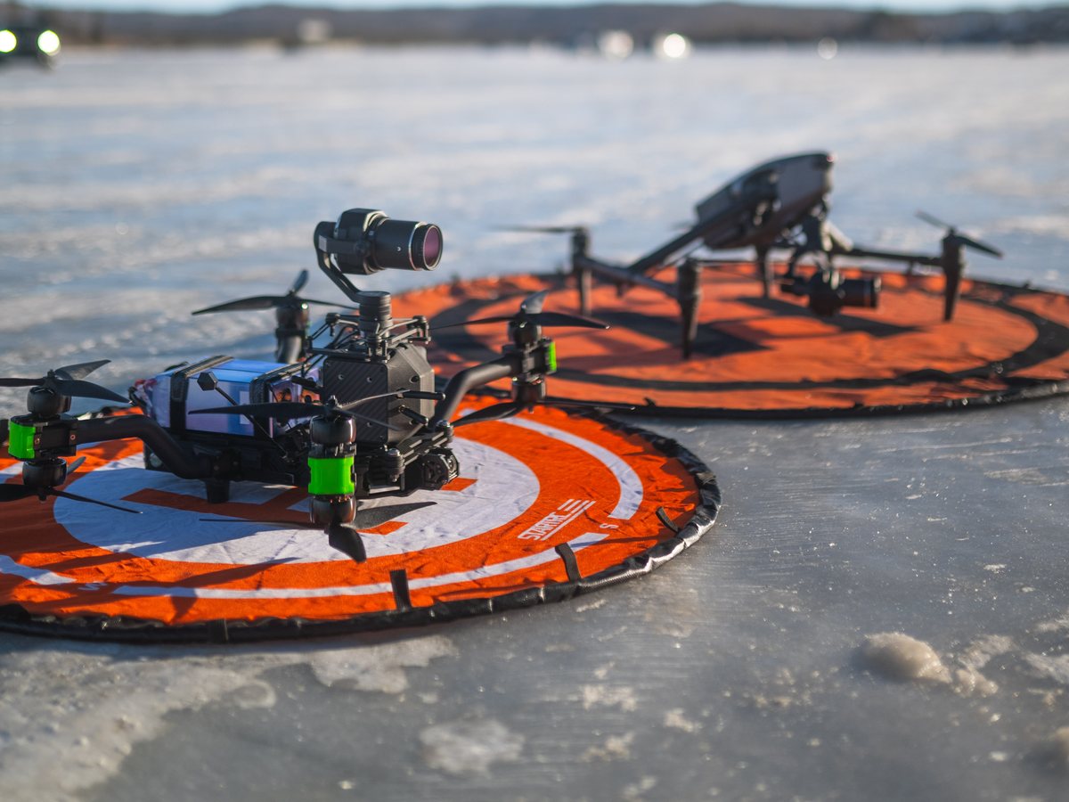 DJI Inspire 3 and an FPV cinelifter staged on landing pads on a frozen Alberta lake